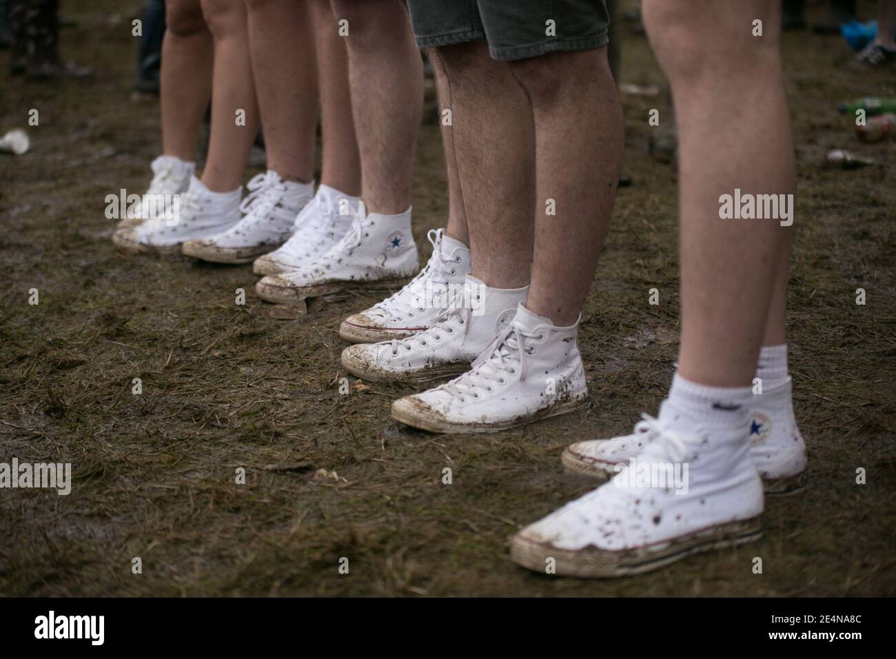 Male Festival Goers standing in the mud wearing new white canvas converse  all star trainers at V Festival Stock Photo - Alamy