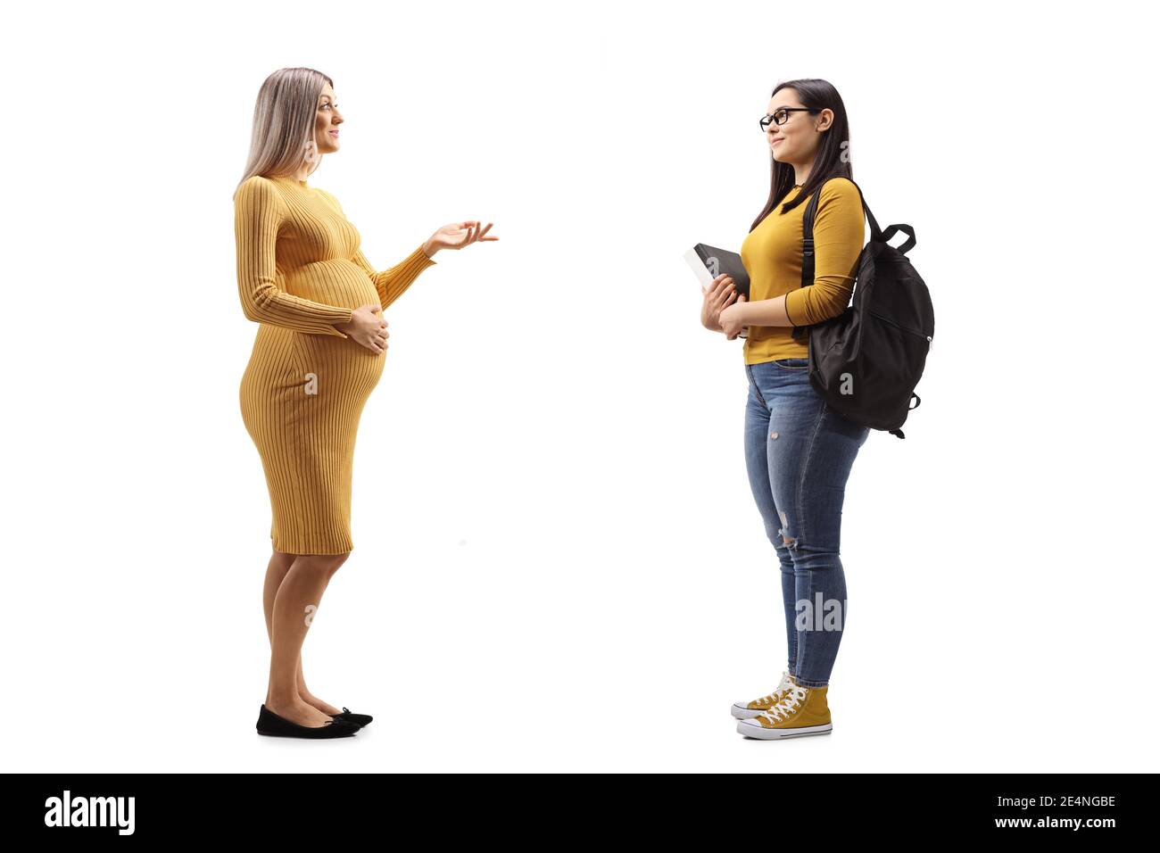 Full length profile shot of a pregnant woman in a yellow dress talking to a student with books isolated on white background Stock Photo