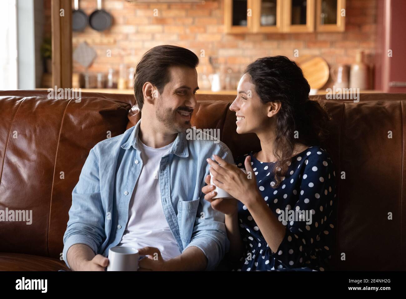 Happy couple relax on sofa drinking coffee talking Stock Photo
