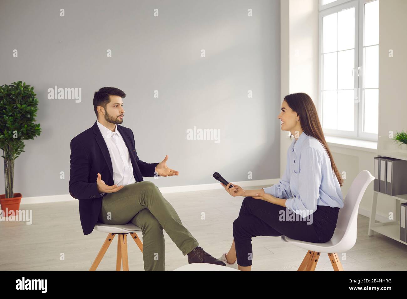 Famous person sitting in TV studio and giving interview to television journalist Stock Photo