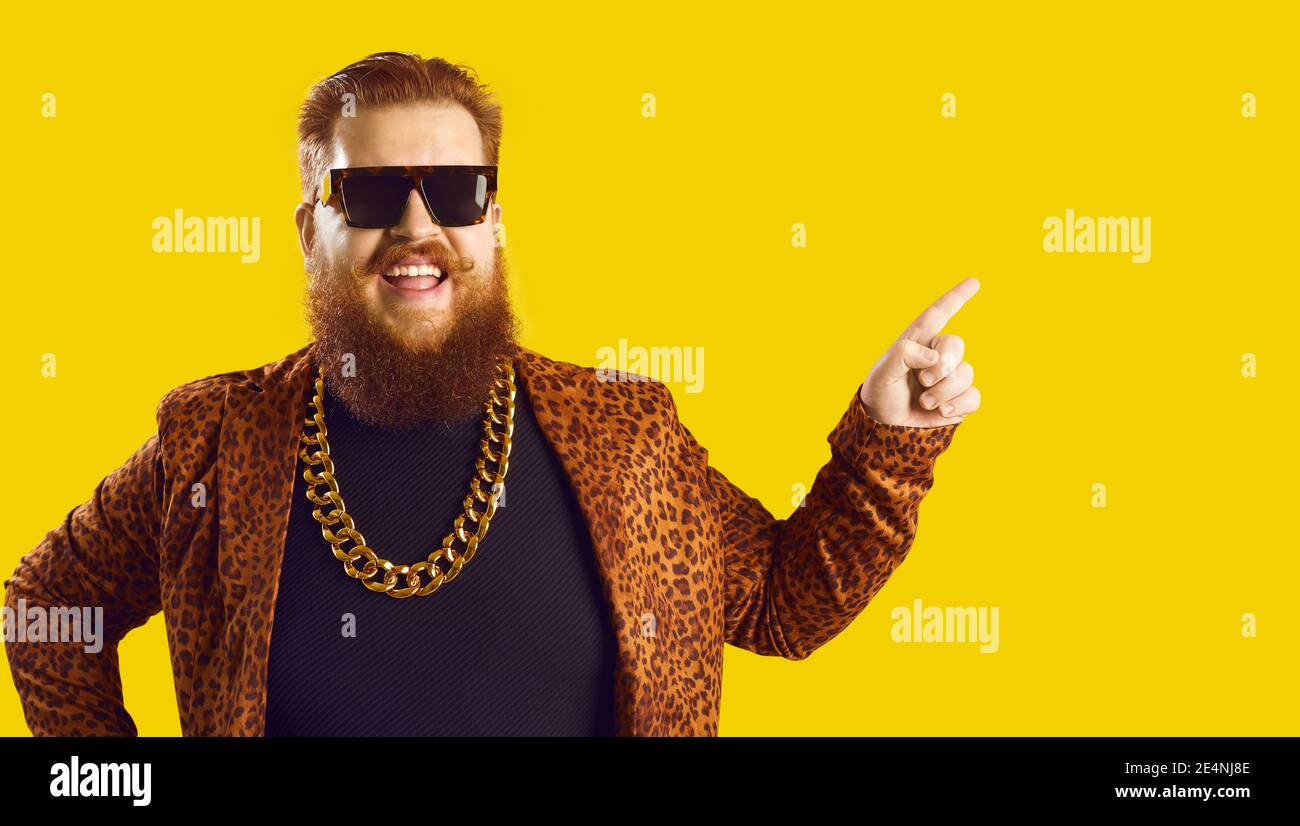 Funny smiling red haired bearded man hipster in leopard jacket pointing aside Stock Photo