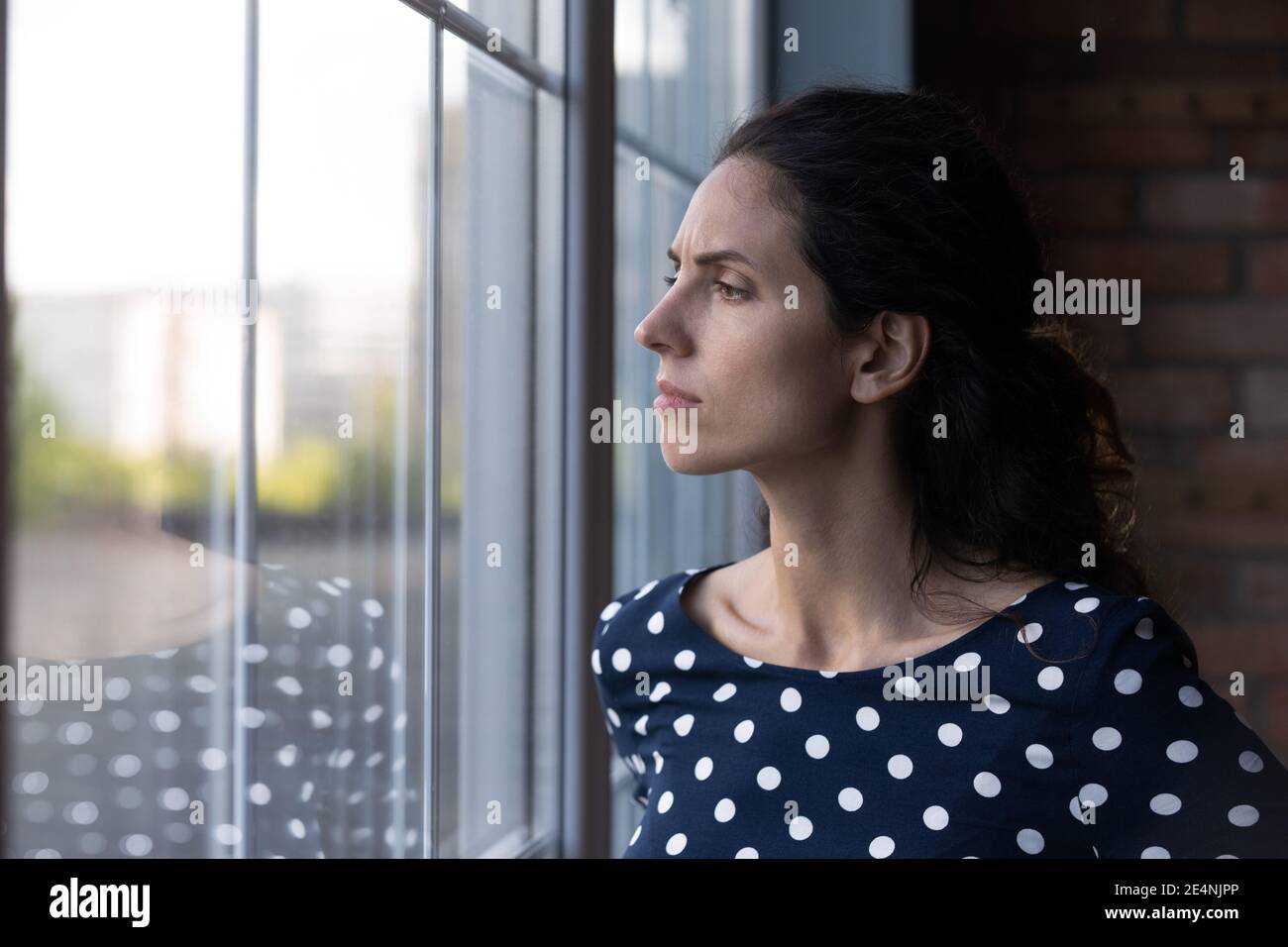 Unhappy woman look in window feeling worried Stock Photo