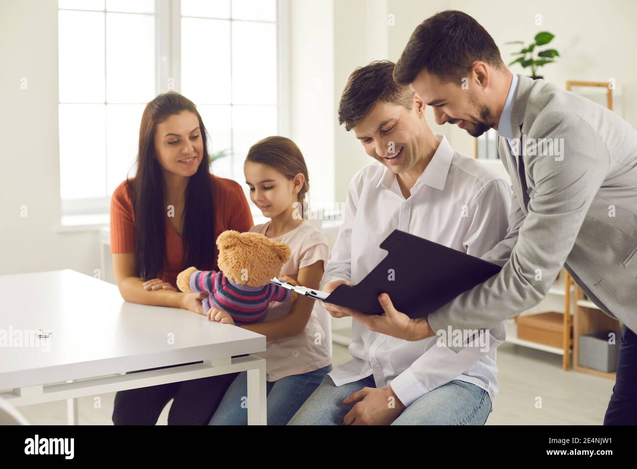 Happy couple with child meeting with bank manager, financial adviser or real estate agent Stock Photo