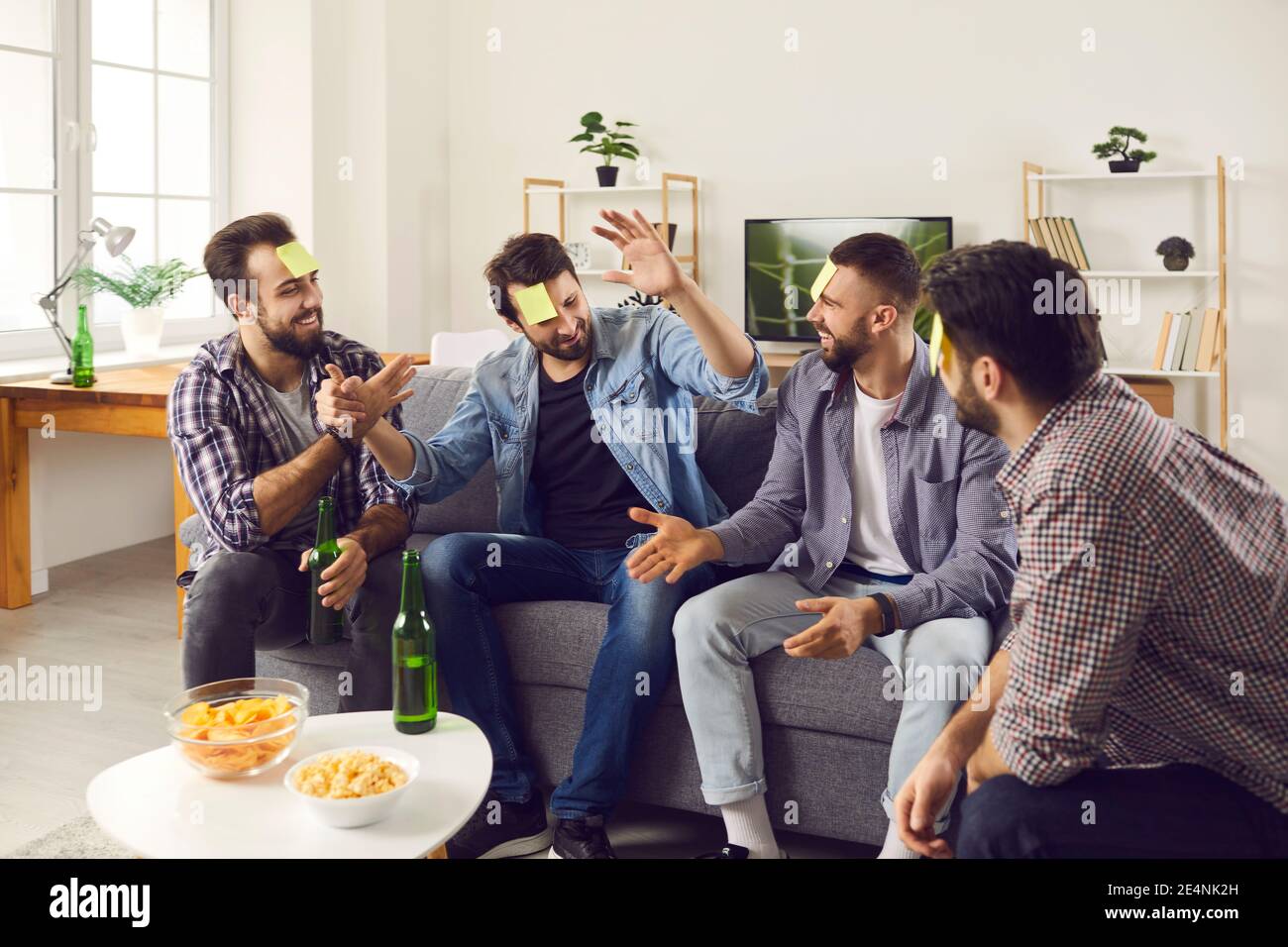 Friends sitting on sofa at home and playing Who Am I guessing game with post-it  notes Stock Photo - Alamy