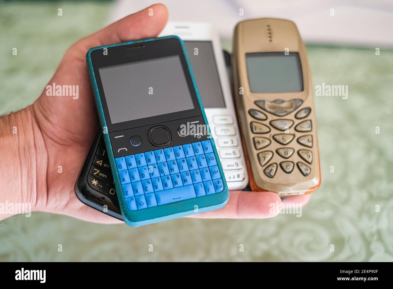 Man hand while hold pile of old gen mobile phones,technology concept Stock Photo