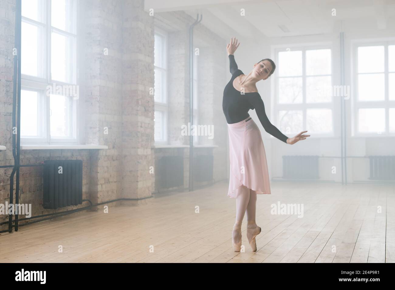 Young beautiful woman ballet dancer dressed in professional outfit pointe shoes and white tutu dancing in studio Stock Photo
