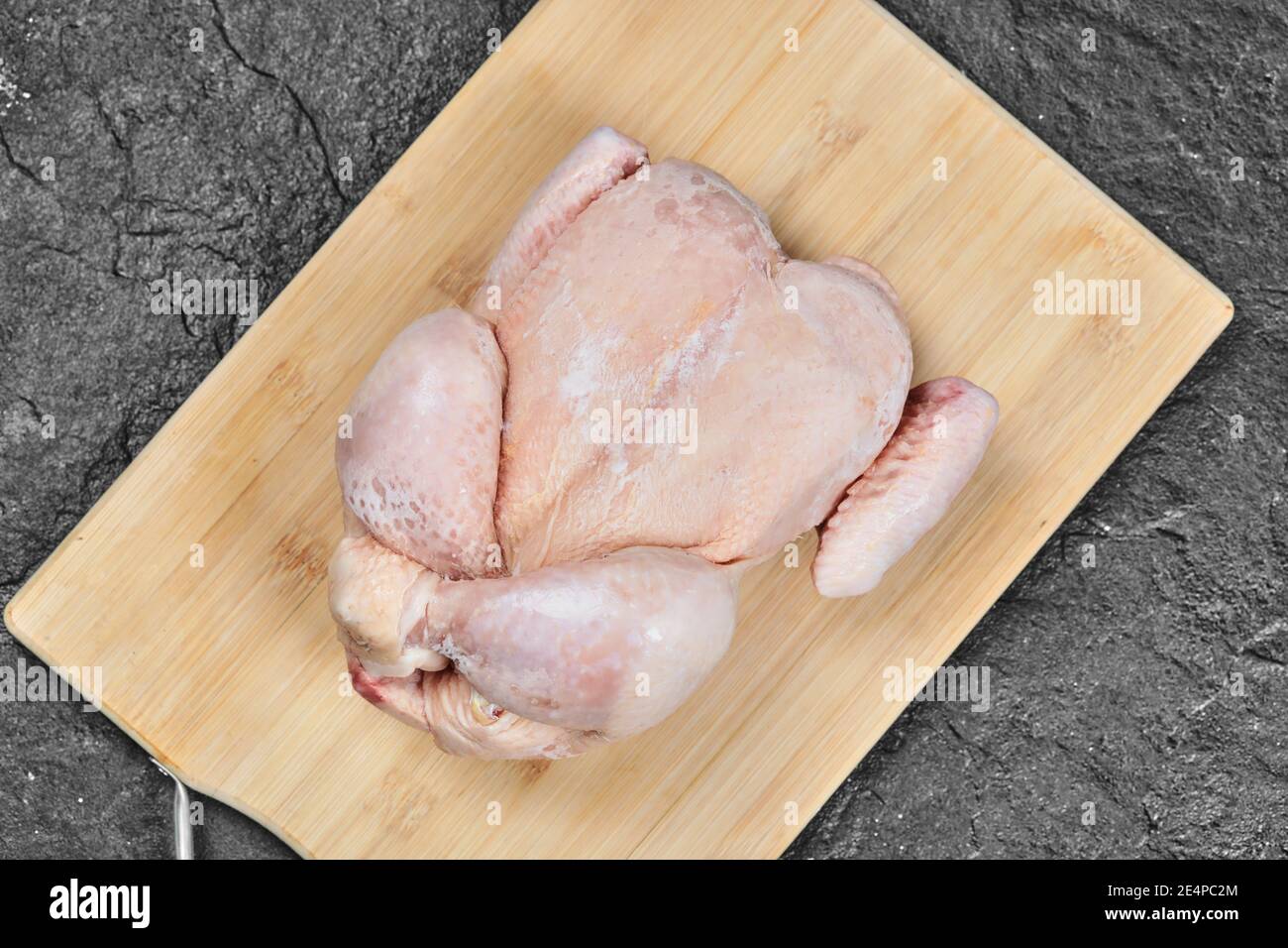 Raw whole chicken on wooden chopping board Stock Photo