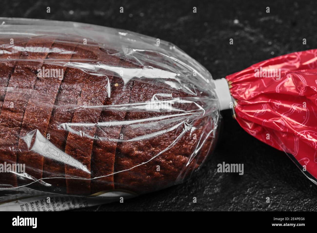Sliced black rye bread in plastic bag on dark background Stock Photo