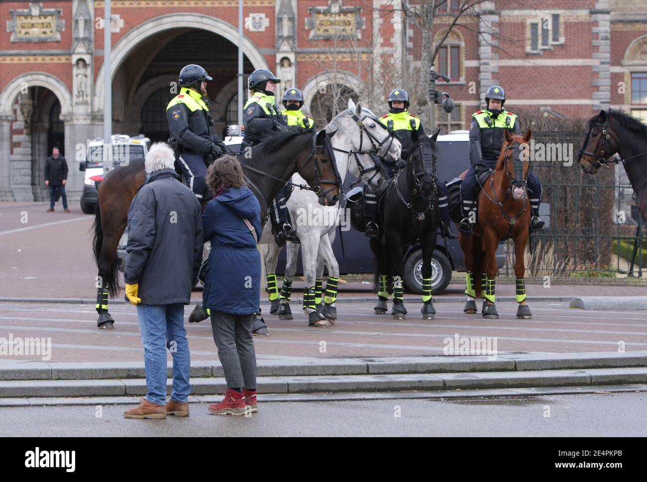 Two anti-lockdown protestors watch the Dutch anti-riot mounted police patrol an illegal demonstration at the Museumplein amid the coronavirus pandemic Stock Photo