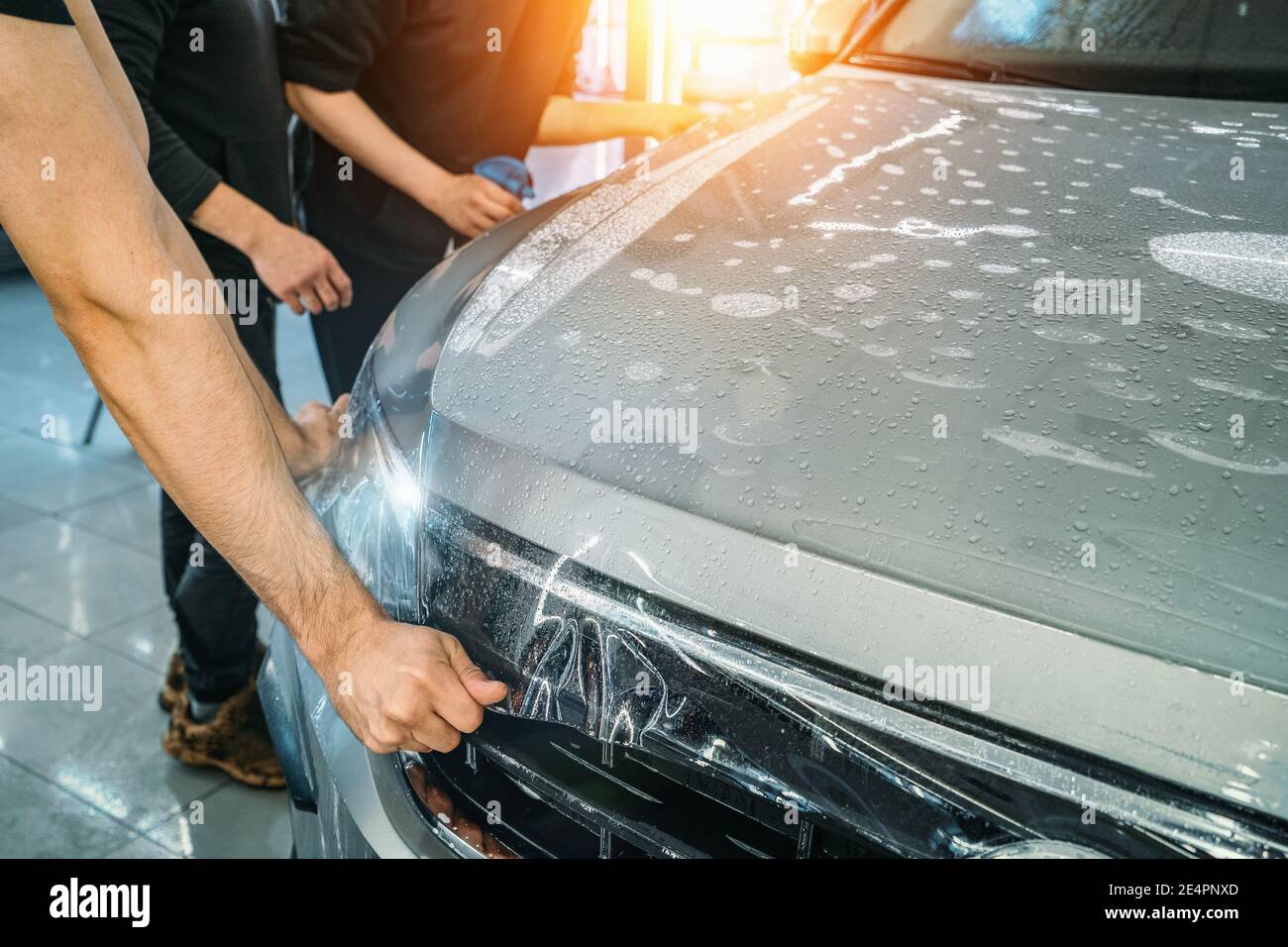 Process of installing of Paint Protection Film or PPF on new car in professional auto Detailing Center. Thin polyurethane film or polymer as protective skin from scratches and rock chips. Stock Photo