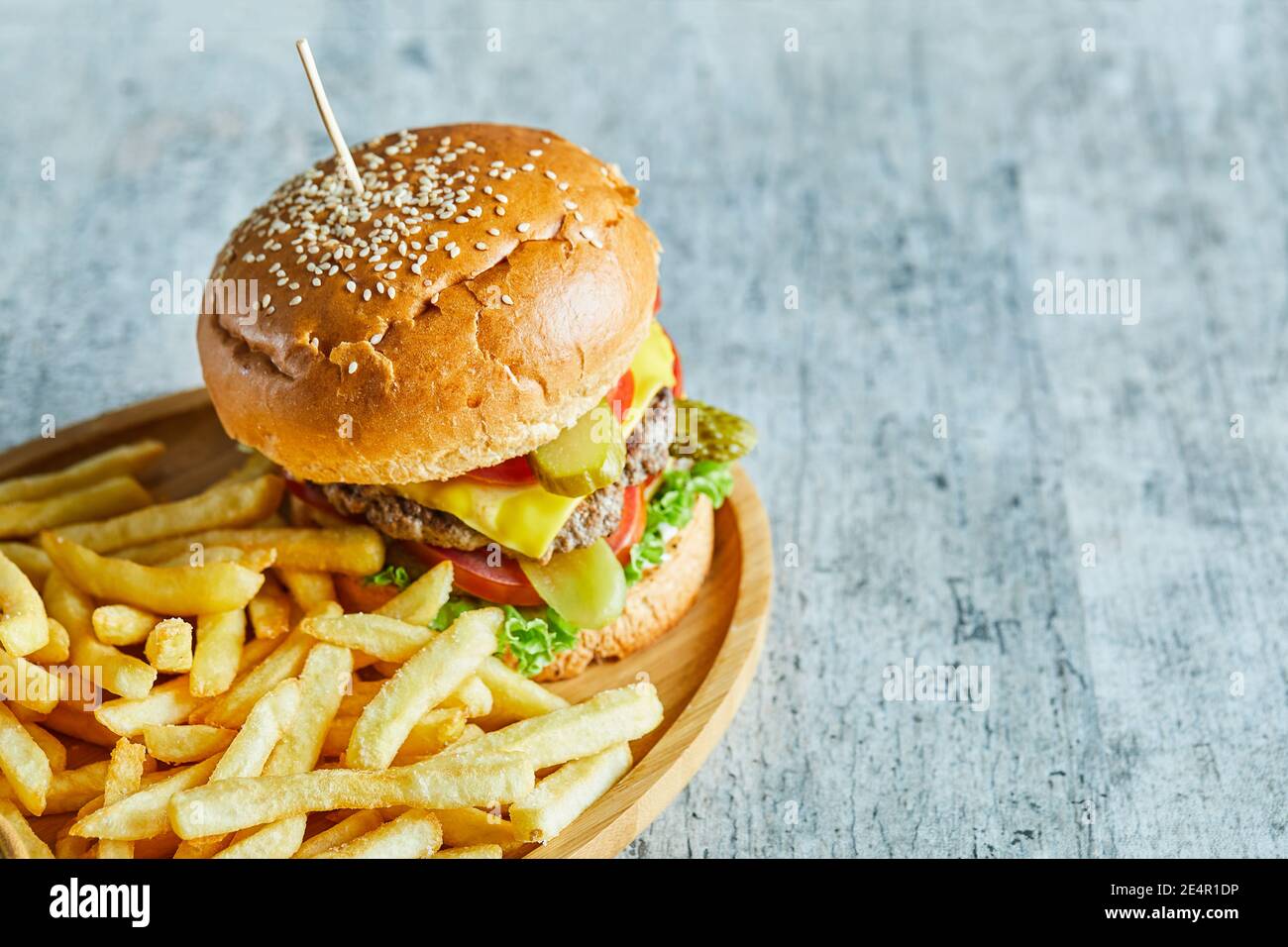 Big burger with fry potato in the wooden plate on the marble background Stock Photo