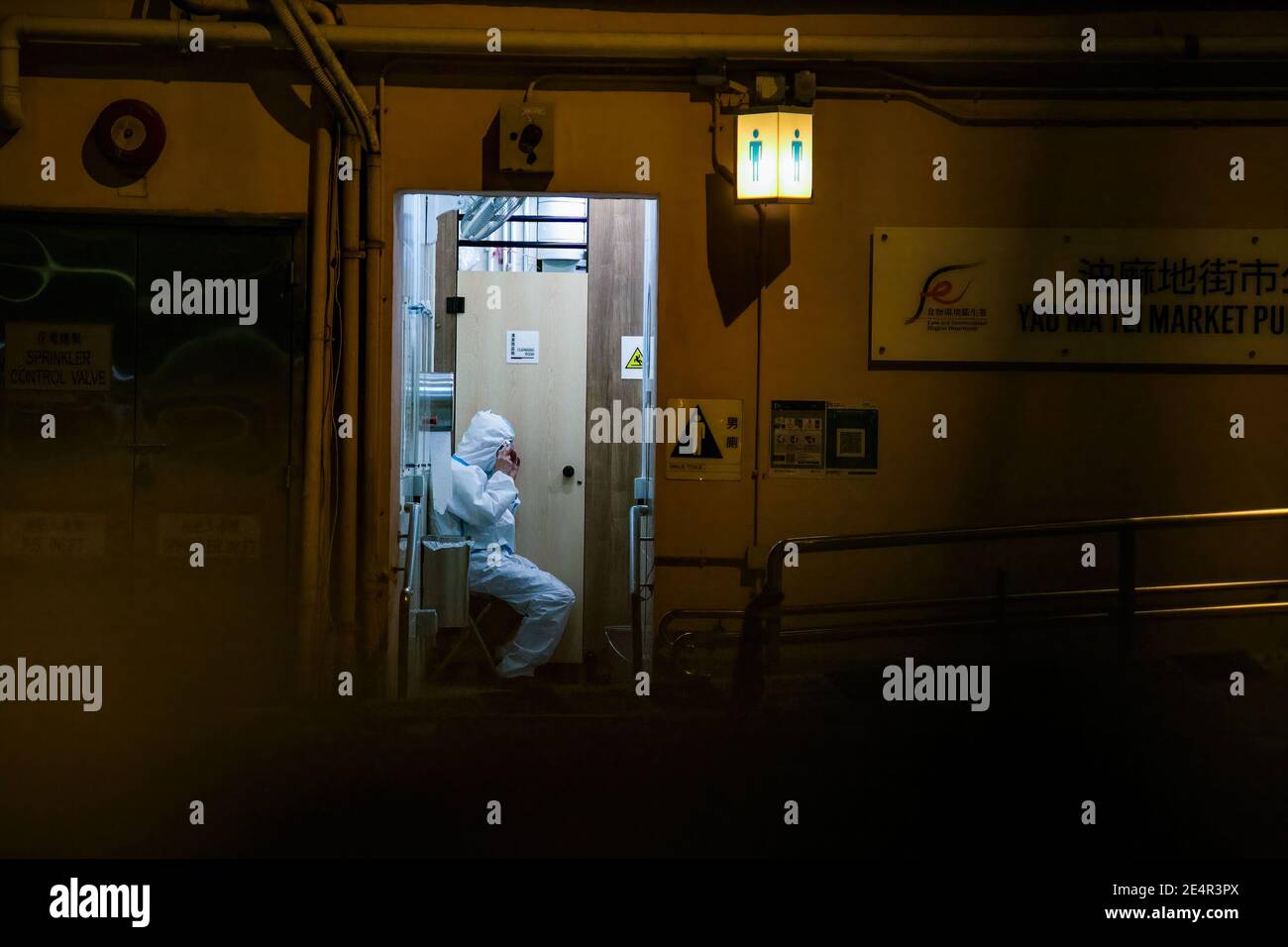 A cleaner wearing a protective suit seen inside a public toilet in an