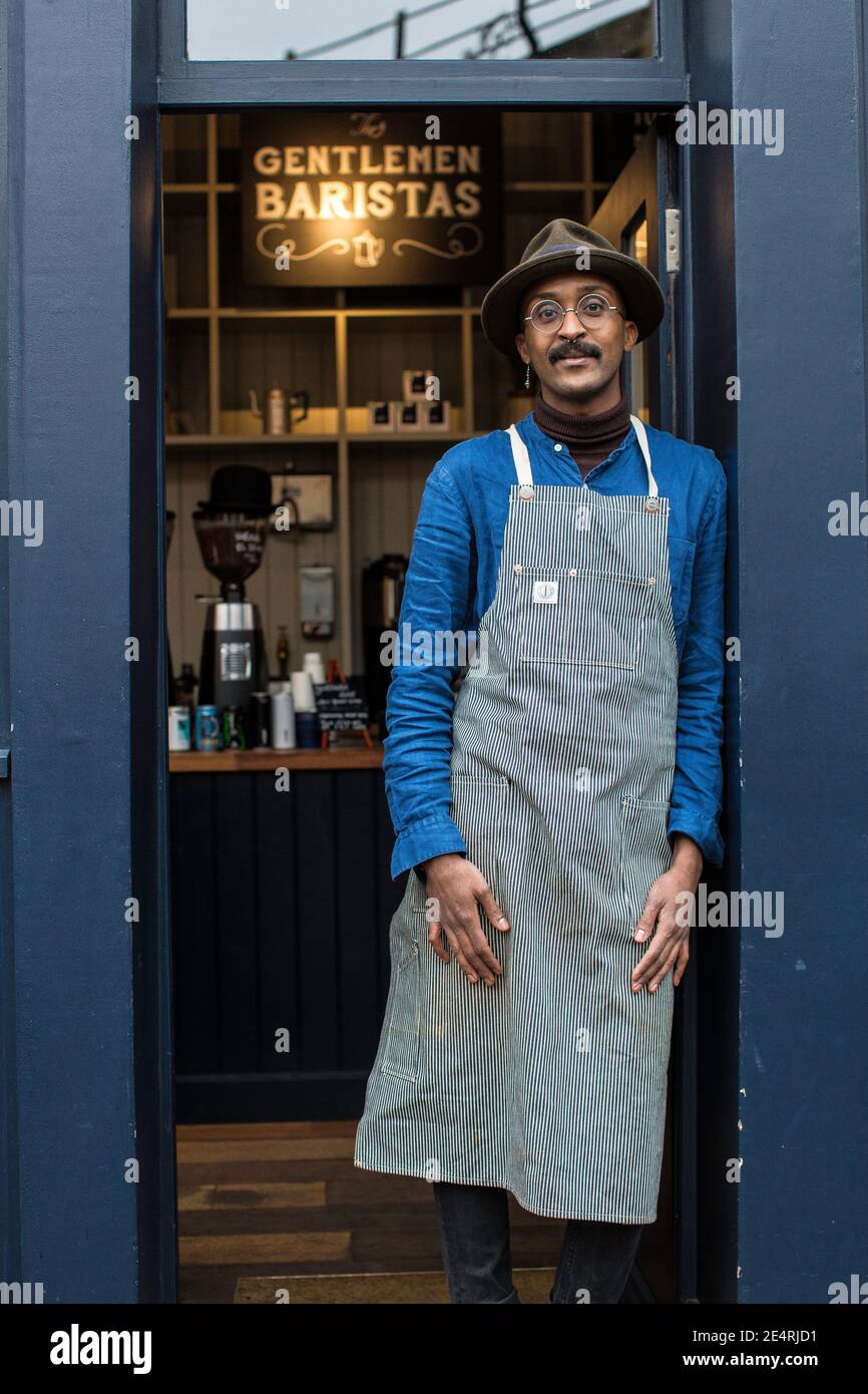 Male Barista cafe owner wearing apron outside coffee shop, food and drink business start up. Stock Photo