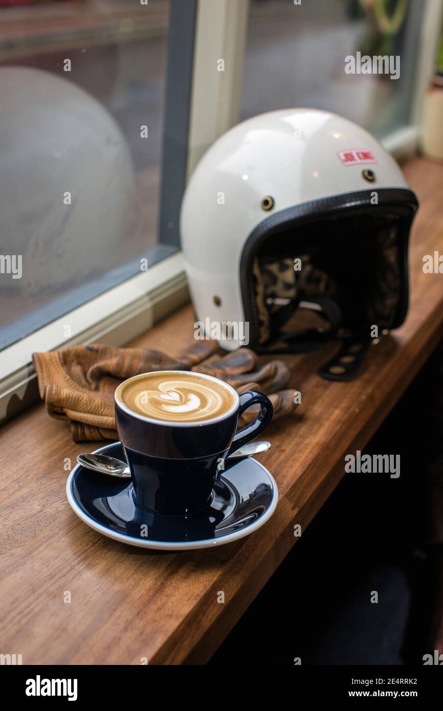 motorcycle helmet in vintage style put on a table in a cafe next to a cup of coffee Stock Photo