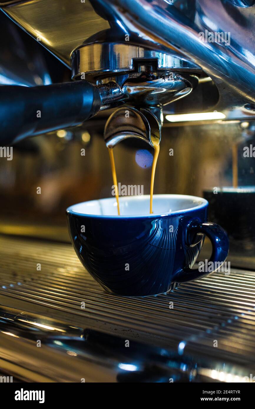 https://c8.alamy.com/comp/2E4RTYR/fresh-espresso-dripping-from-portafilter-of-coffee-machine-into-black-cup-2E4RTYR.jpg