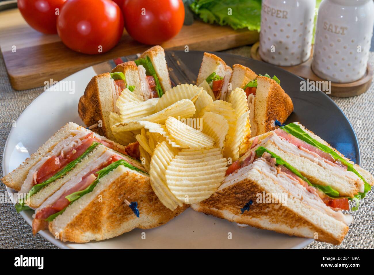 Fresh turkey club sandwich on white toast with potato chips on a plate Stock Photo