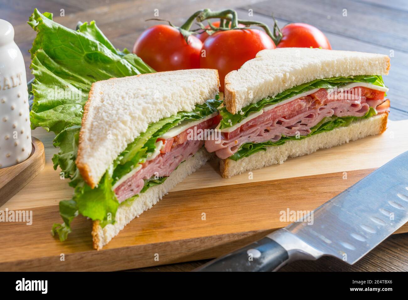 Fresh ham, tomato and cheese sandwich on cutting board Stock Photo