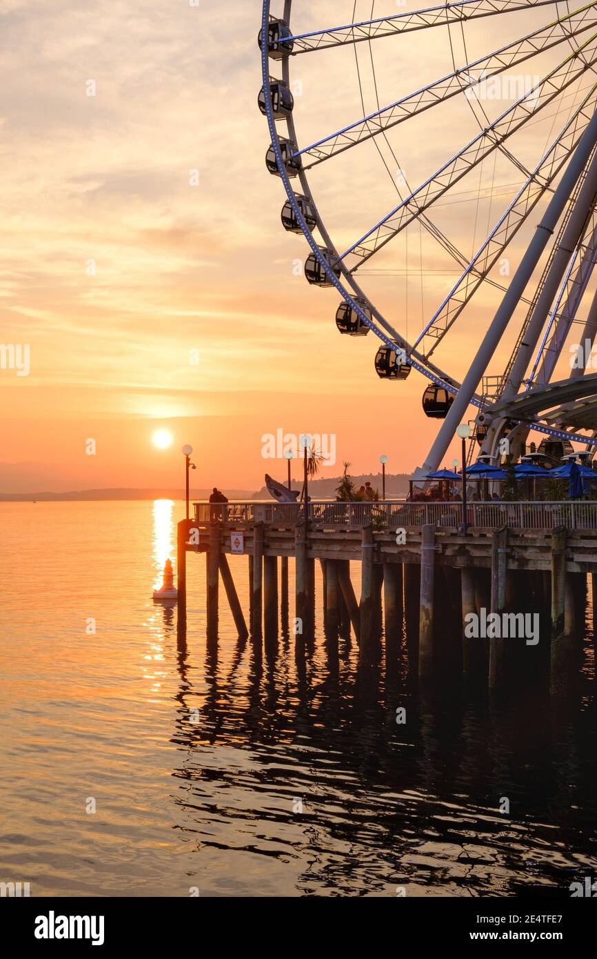 The Seattle Great Wheel rises 175 feet over Pier 57, overlooking the Seattle skyline and Elliott Bay as the sun sets in the west Stock Photo