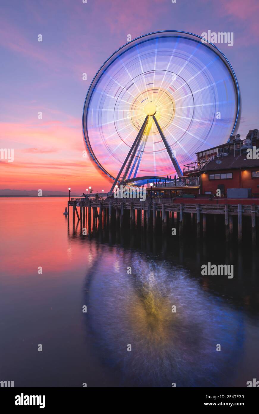 The Seattle Great Wheel rises 175 feet over Pier 57, overlooking the Seattle skyline and Elliott Bay as the sun sets in the west Stock Photo