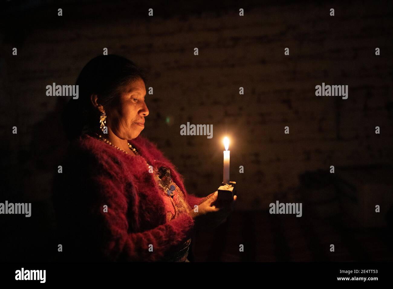 A woman uses a candle as a light source at her home in Cantel, Guatemala, Central America. Stock Photo