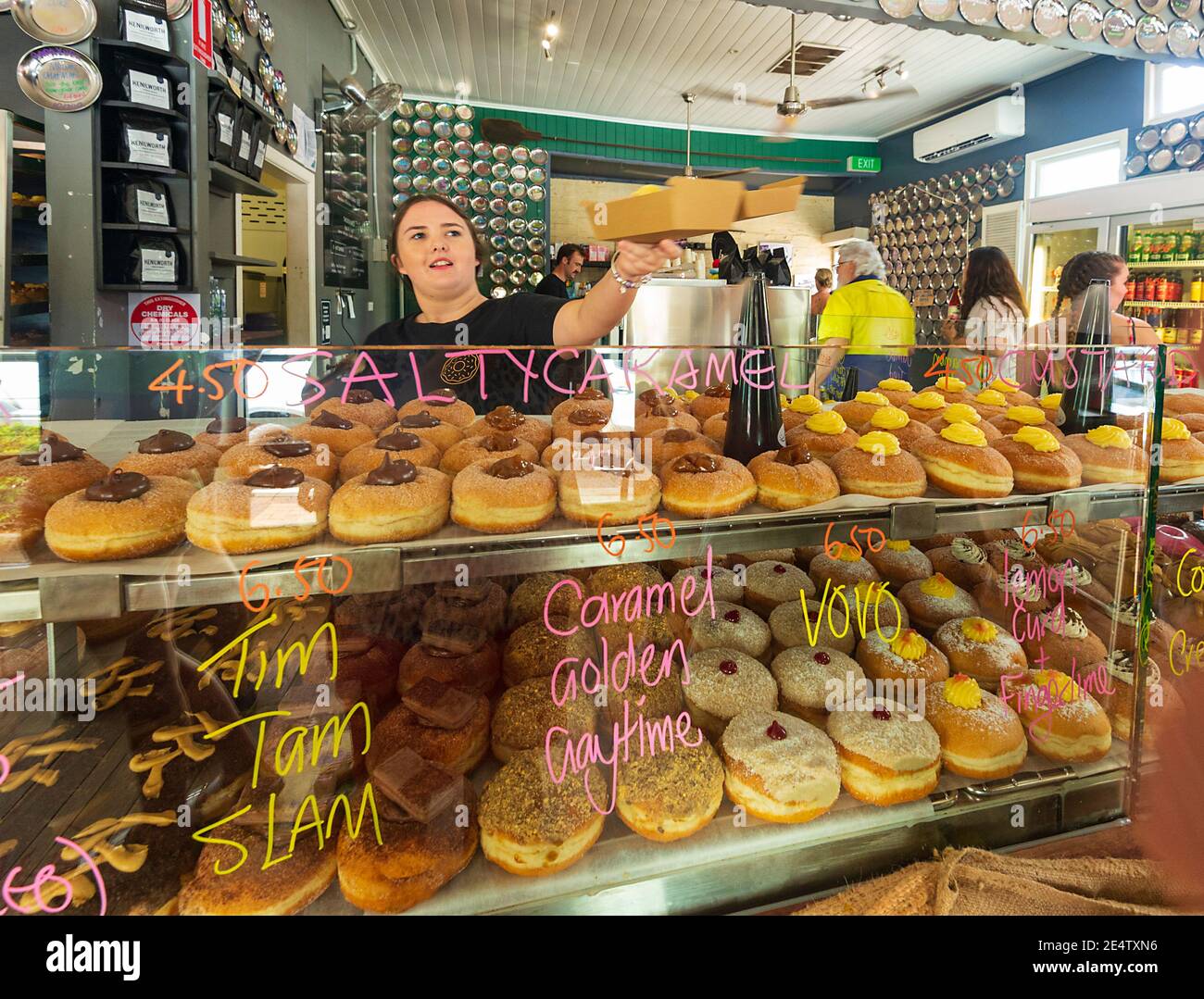 Young female staff selling doughnuts inside the Kenilworth Country Bakery, South East Queensland, QLD, Australia Stock Photo