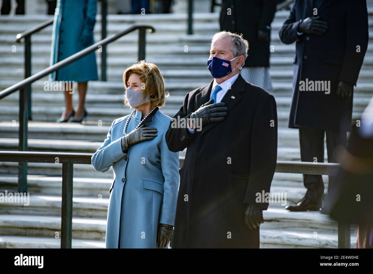 Former President George W. Bush and former First Lady Laura Bush, stand for the national anthem during a wreath ceremony at Arlington National Cemetery, part of the 59th Presidential Inauguration events January 20, 2021 in Arlington, Virginia. Stock Photo