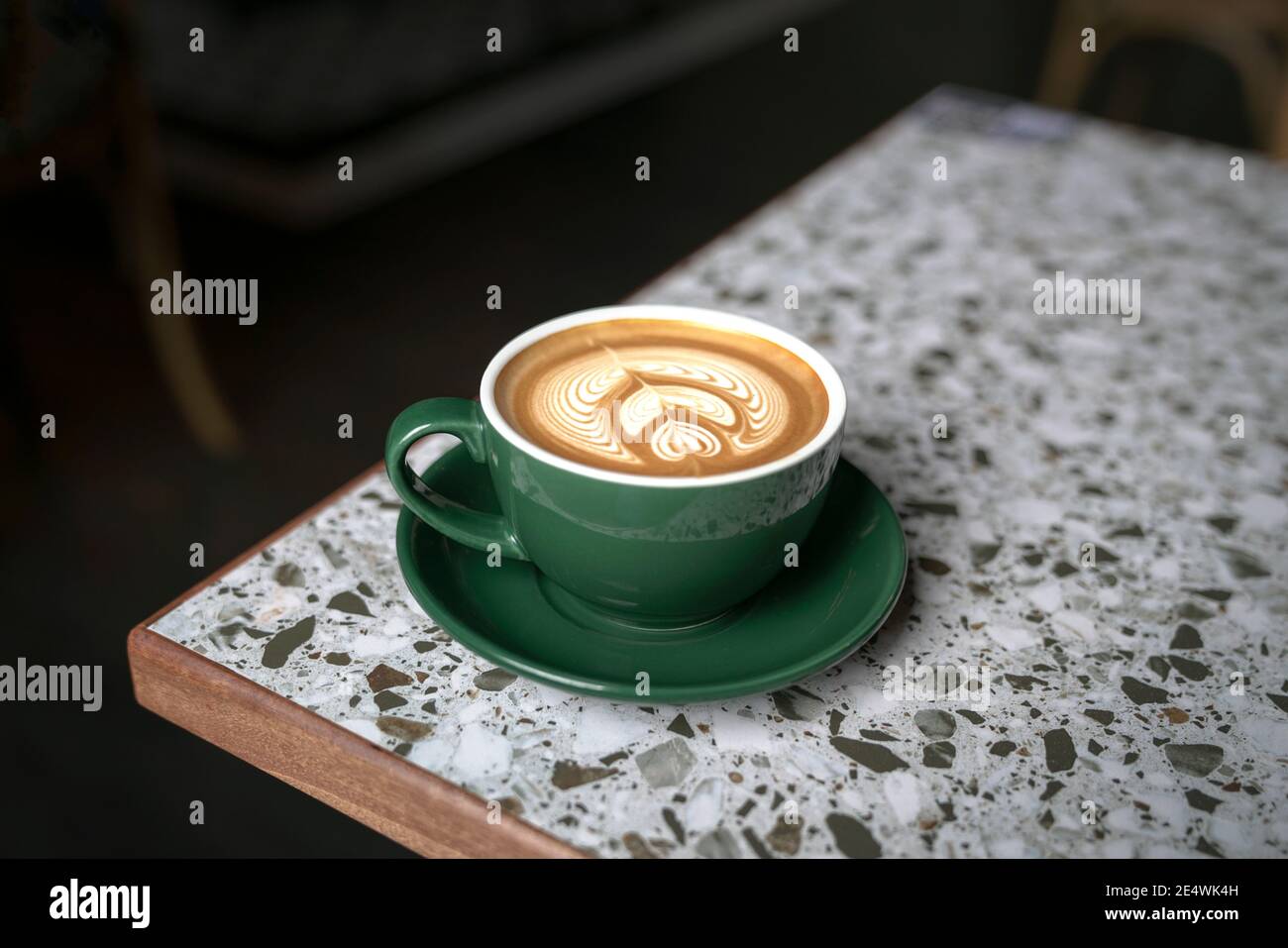 Cup of Flat White coffee in a green cup with beautiful latte art, on marble table. Stock Photo