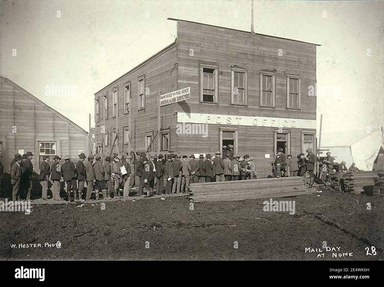 Men lined up at the Post Office to receive mail, Nome, Alaska, ca 1900