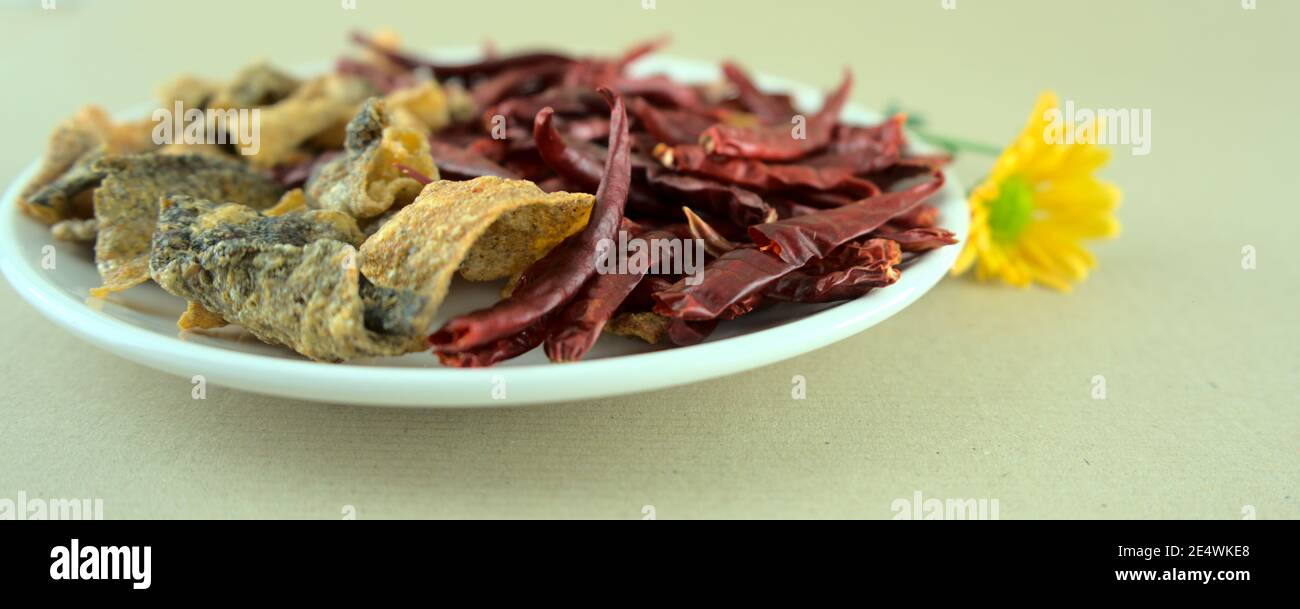 Crispy salted fish skins with dried red hot chilis. Fired, baked snack or starter. Spicy asian food style photography, ocean products, merchant. Stock Photo