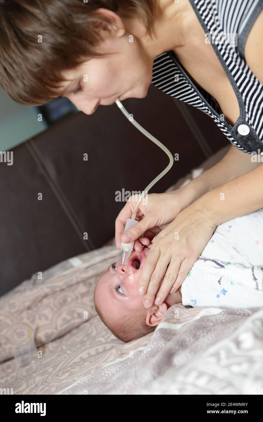 Mother using nasal aspirator for her son Stock Photo