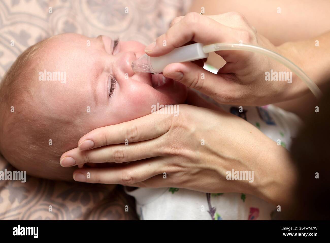 Mother treats her son with nasal aspirator at home Stock Photo