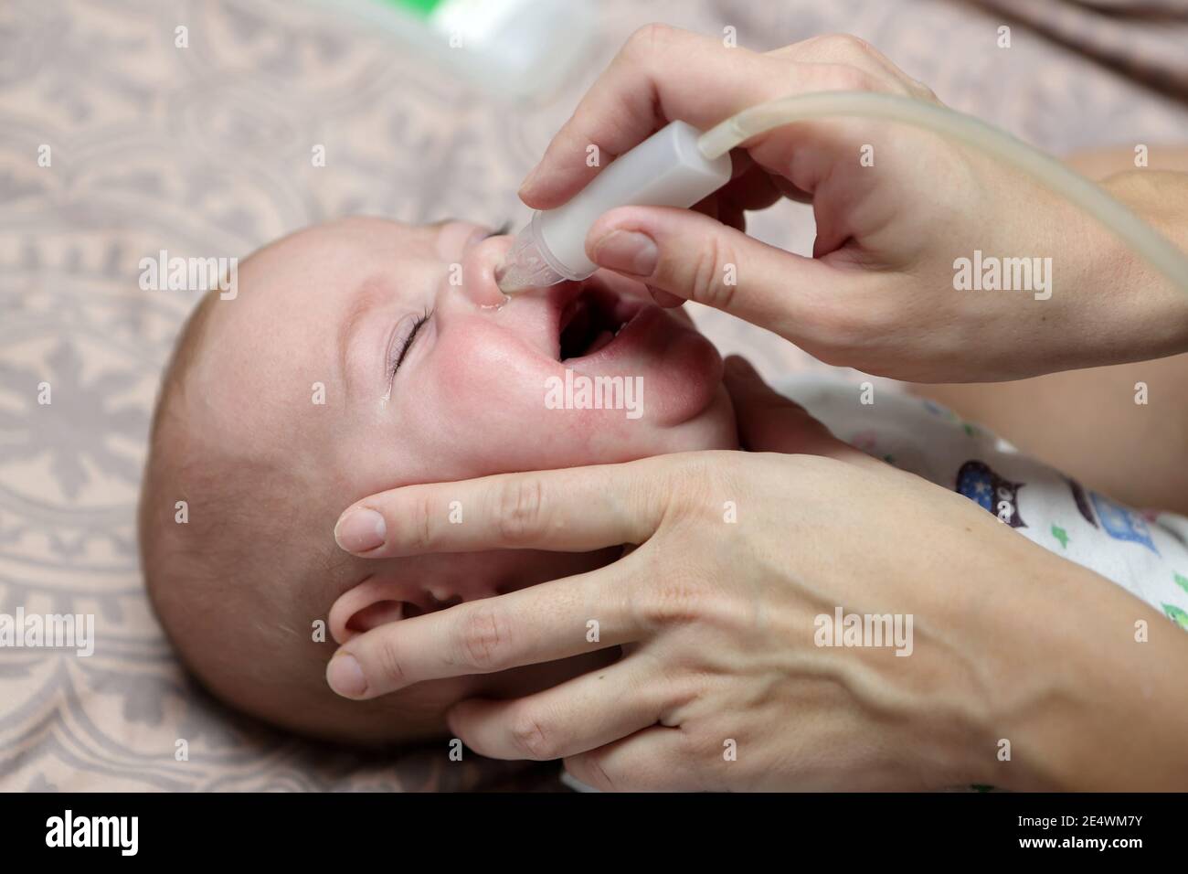 Mother using baby's nasal aspirator at home Stock Photo