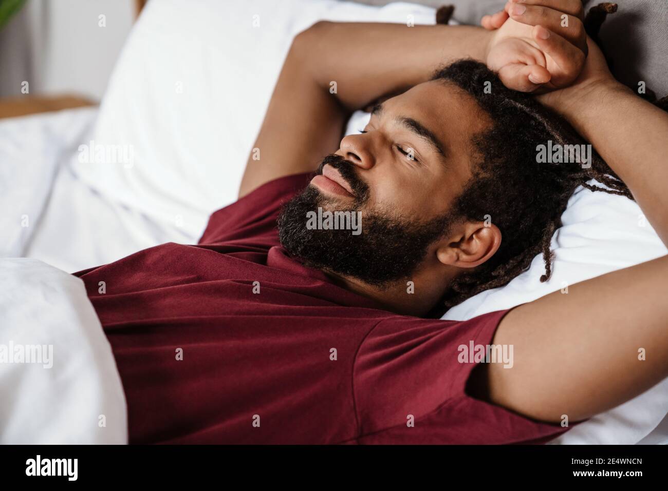 Tired young african-american man sleeping in bed Stock Photo