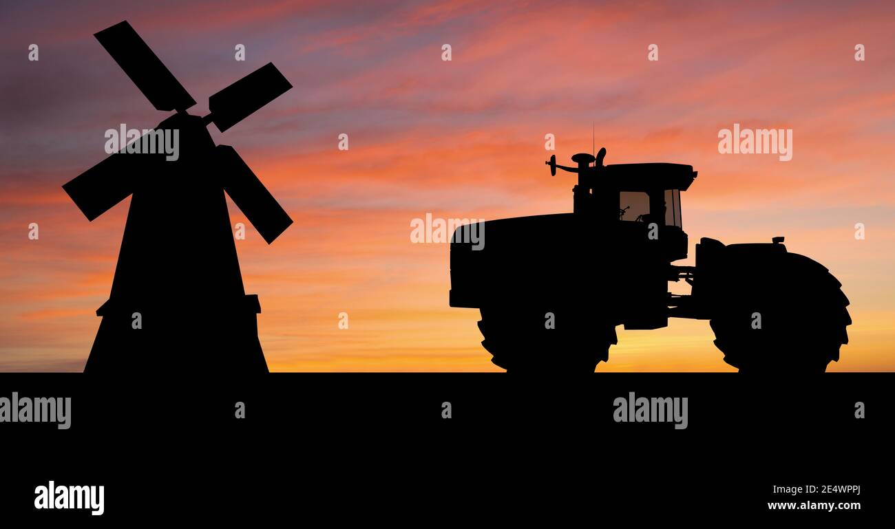 Silhouettes of a tractor and windmill Stock Photo