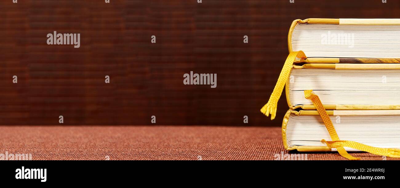 Wide bookshelf banner with a stack of books with bookmarks. Background