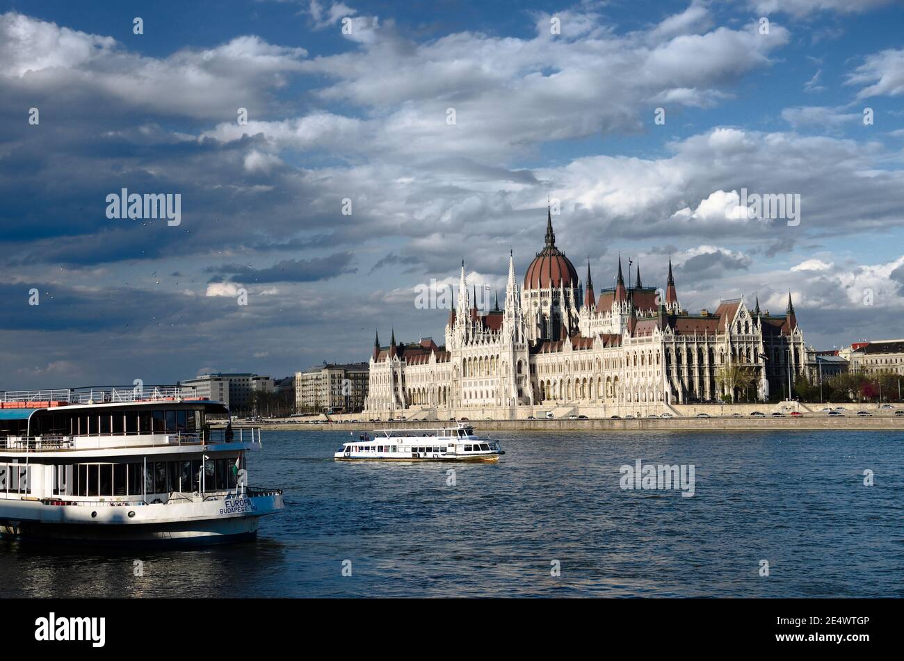 Budapest, Hungary - April 04, 2012: tourist boat called Europa Budapest, Hu is moored on the Danube River and another is cruising in front of the Hung Stock Photo
