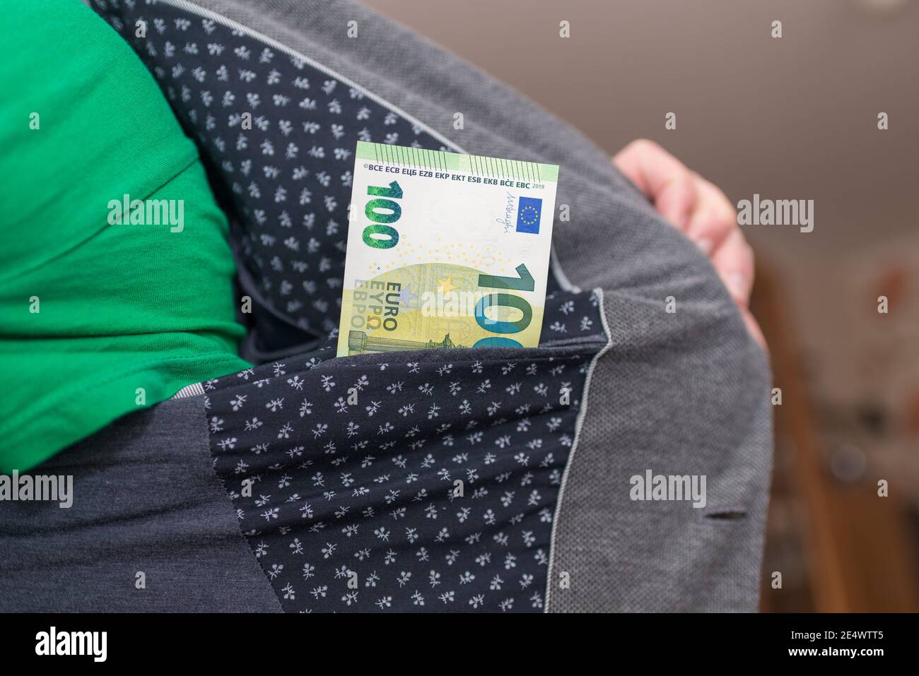 One hundred euros and a man's jacket pocket indoors shot.Blurred background. Stock Photo
