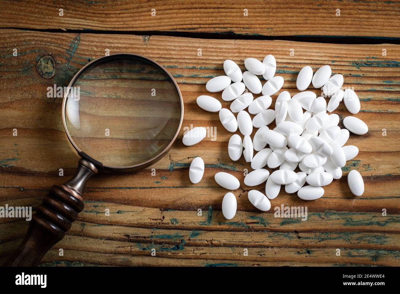 Magnifying glass and white medicine on a wooden background. Research
