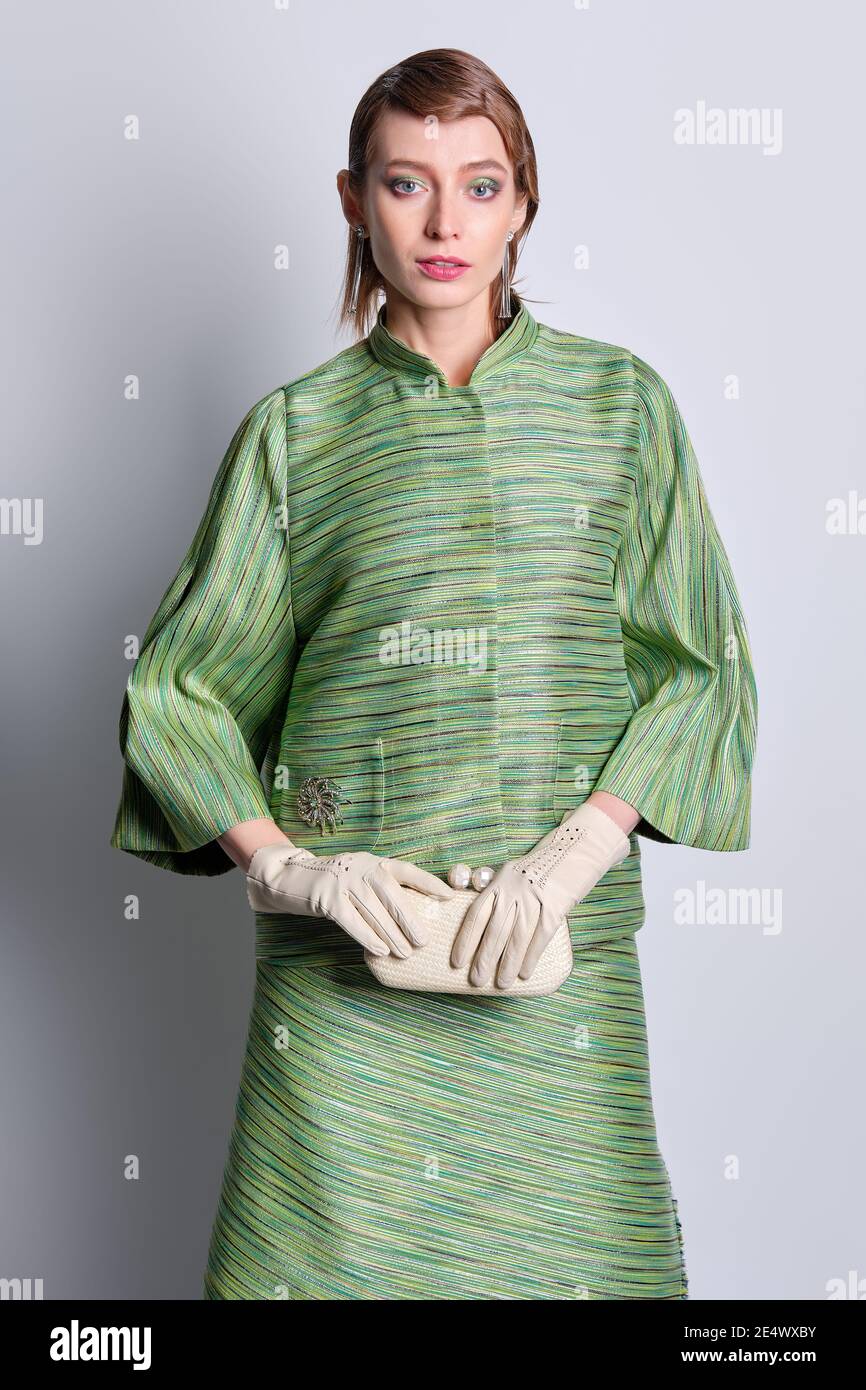 Beautiful fashion model in silk green jacket and skirt with old