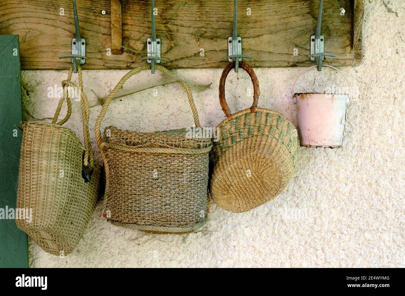 Collection or Display of Old Straw Bags or Baskets Hunging from Wall Hooks Stock Photo