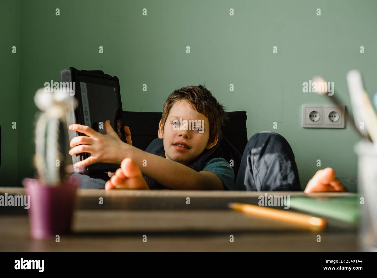 Smiling boy using tablet at home, growing up with technology Stock Photo