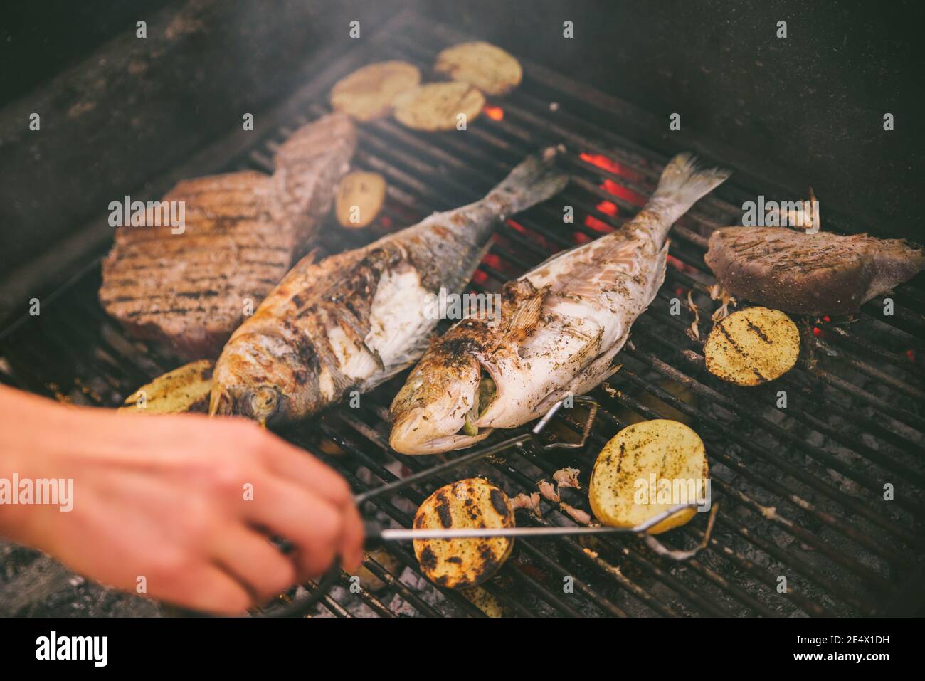 cooking fish and potatoes on grill outdoors Stock Photo - Alamy