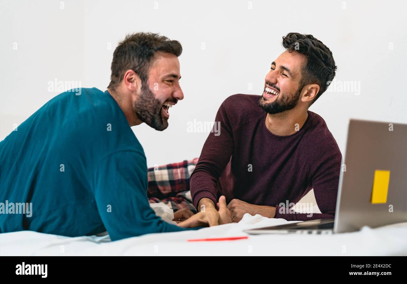 Happy gay men couple using laptop in bed - Homosexual love and gender equality in relationship concept Stock Photo