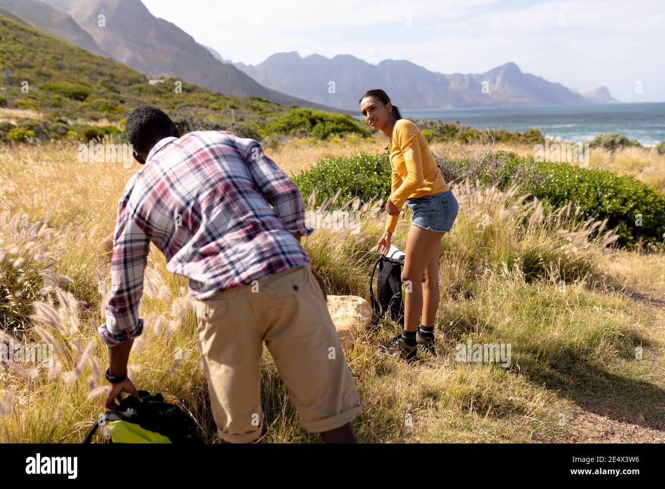 Fit african american couple resting putting backpacks down in mountain countryside Stock Photo