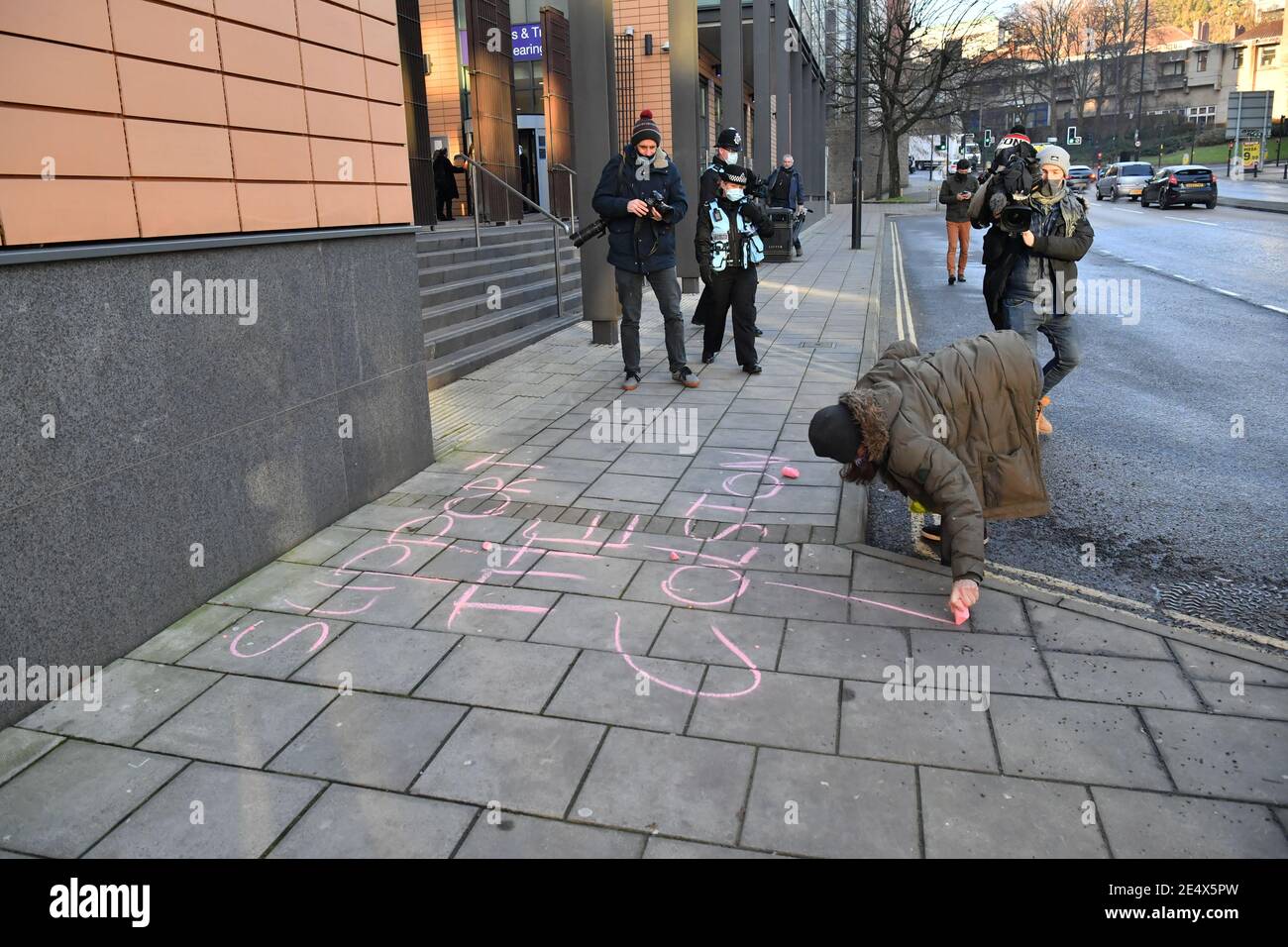 A woman writes 'Support the Colston 4' in chalk outside Bristol Magistrates' Court, where Rhian Graham, Milo Ponsford, Jake Skuse and Sage Willoughby are due to appear charged with criminal damage over the toppling of the Edward Colston statue in Bristol during the Black Lives Matter protests in June last year. Picture date: Monday January 25, 2021. Stock Photo