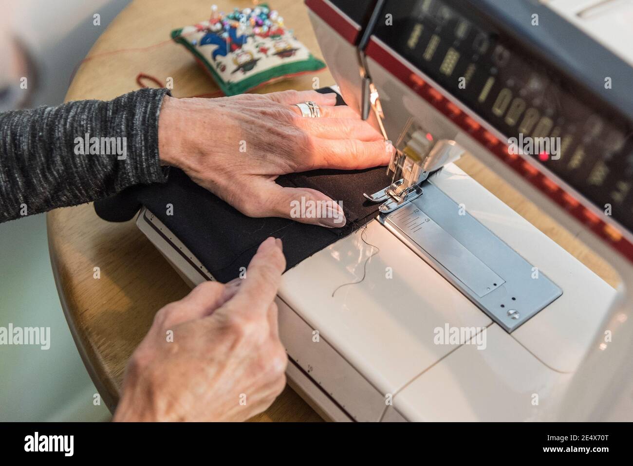 A woman using a sewing machine to sew material. Stock Photo