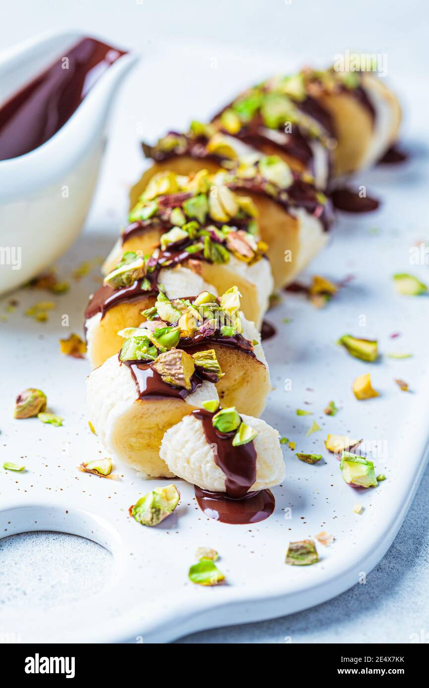 Sweet banana sushi with chocolate and nut, white background. Vegan dessert concept. Stock Photo