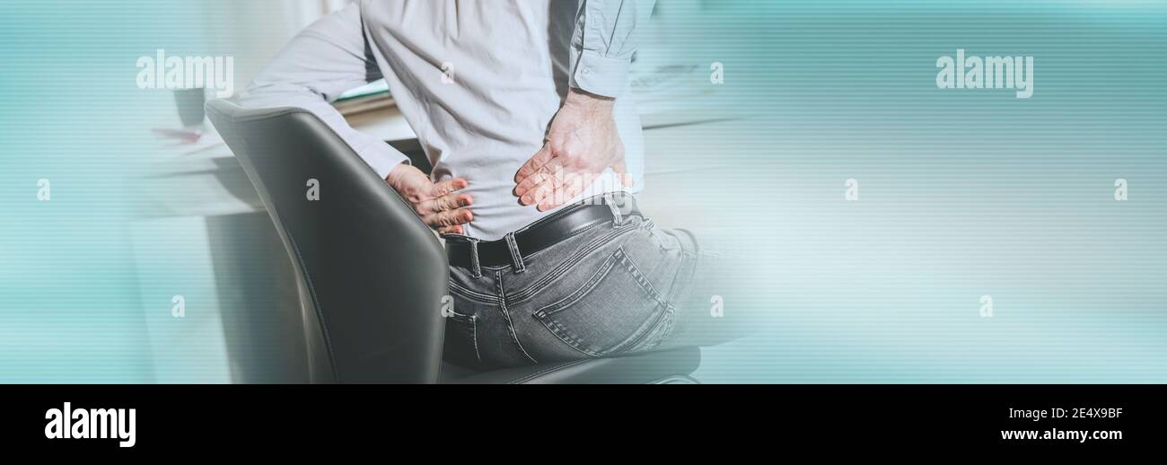 Businessman suffering from back pain in office, light effect; panoramic ...