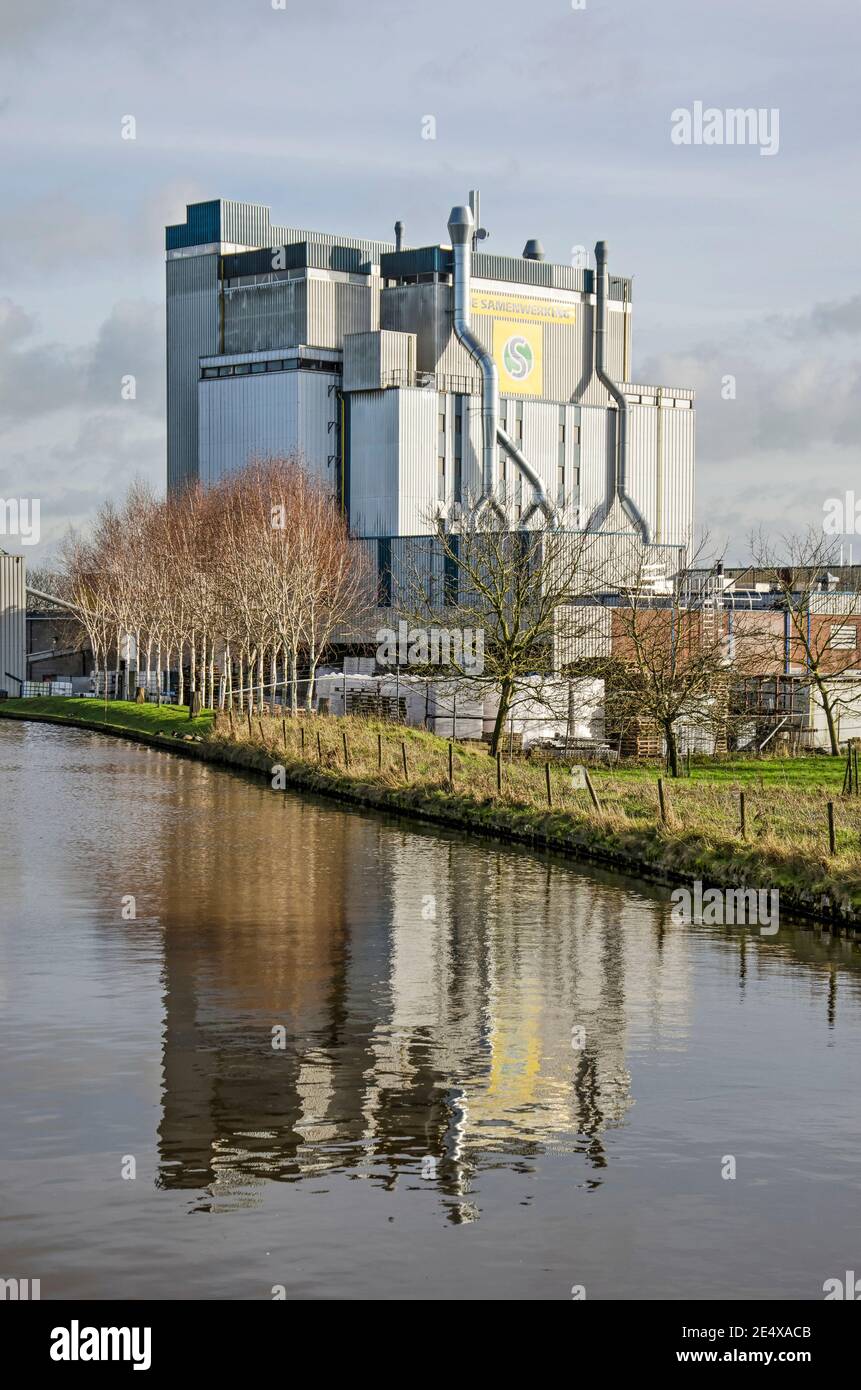 Haastrecht, The Netherlands, January 22, 2021: Cattlefeed factory reflcting in the water of the river Hollandsche IJssel on a sunny day in winter. Stock Photo
