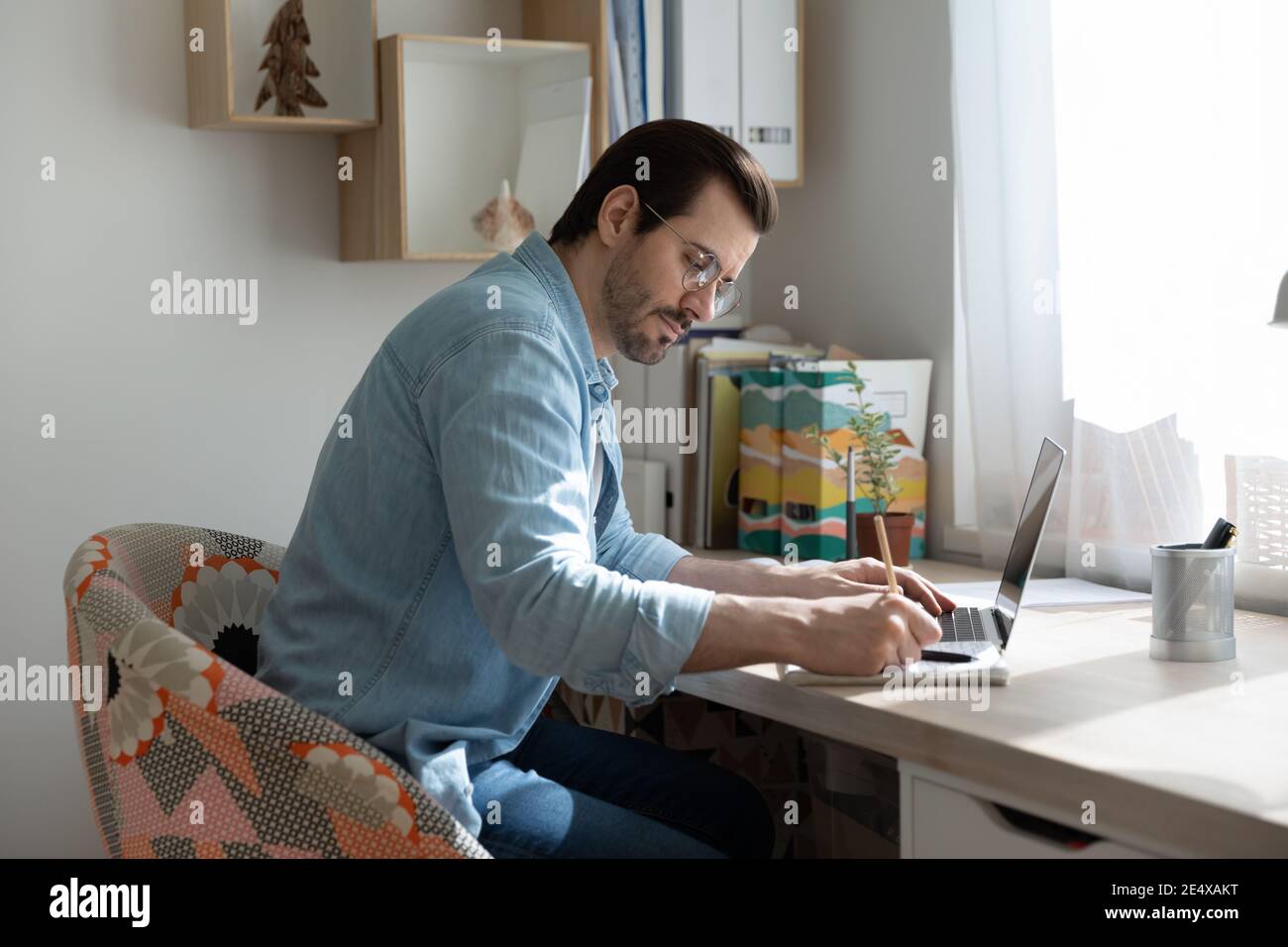 Young man making notes from online tutorial on distant learning Stock Photo